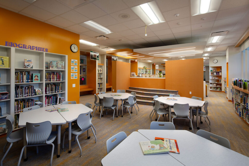 Richards Elementary School library collaboration area with reading stairs, tables and chairs, and books