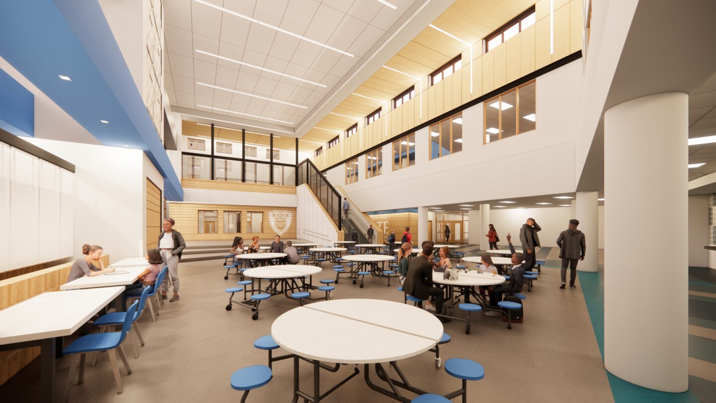 Schulte 4K-8 school commons area with a staircase to the second floor in the far distance and students eating lunch
